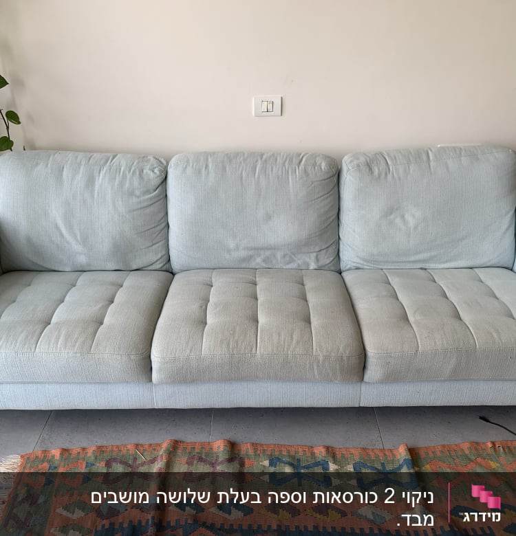 ספה אפורה עם שלושה מושבים על שטיח צבעוני